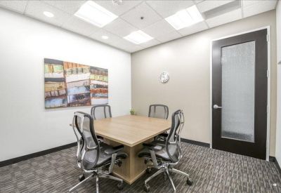 Modern four-person meeting room with a wooden table and framed wall art.