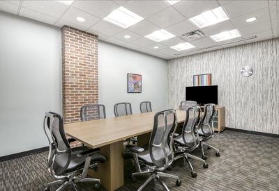 Professional boardroom with a large conference table and a brick feature wall.