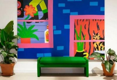 Lounge area with a vibrant wall mural, a green bench, and potted plants.