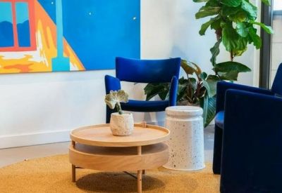 A breakout area featuring blue velvet armchairs and a circular wooden coffee table.