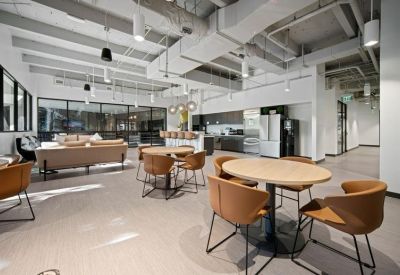 Large communal breakroom with lounge seating, dining tables, and a modern kitchen area.
