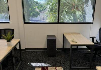 Office space featuring two wooden desks, a filing cabinet, and large windows with garden views.