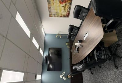 Executive boardroom with a large wooden table, black leather chairs, and wall-mounted TV.