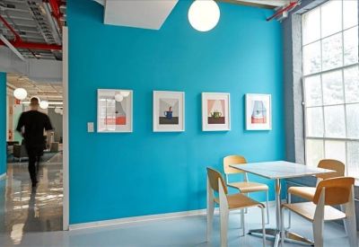 Dining area with a vibrant blue feature wall and modern light-wood furniture.