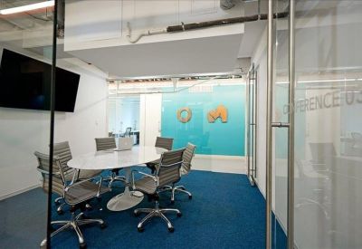 Modern conference room with an oval table and blue carpet seen through a glass wall.