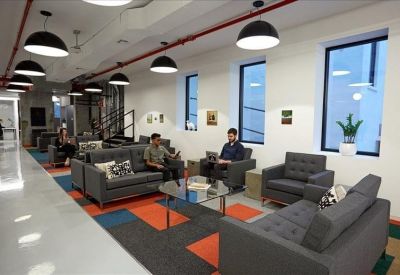Stylish lounge area with gray sofas, a glass coffee table, and a colorful geometric rug.