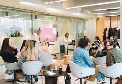 Bright, informal meeting space with a pink screen display and comfortable seating on a rug.