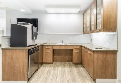 Spacious u-shaped office kitchen with light wood cabinetry and modern appliances.