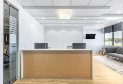 Professional reception desk in a bright lobby with a gray sofa and waiting area.