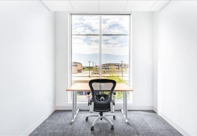 Bright private office suite featuring a large window and ergonomic desk chair.