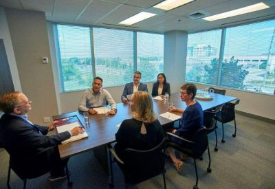 Spacious boardroom with a large wooden table, blue chairs, and expansive window views.