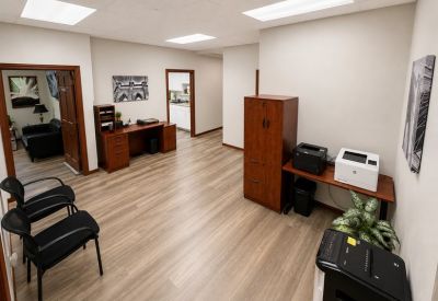 Reception area or common walkway with a storage hutch, printer station, and comfortable guest seating.