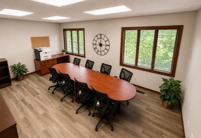 Professional meeting room with a long wooden conference table, ergonomic chairs, and a large decorative wall clock.