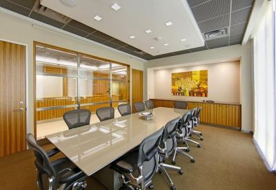 Professional boardroom with a long glossy table, mesh ergonomic chairs, and a colorful feature painting.