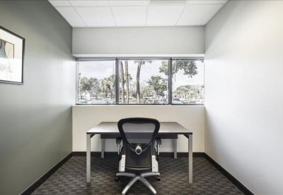 Private windowed office suite with a black ergonomic chair and grey walls.