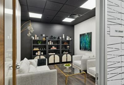Private lounge area with dark gray walls, bookshelves, and white sofas.