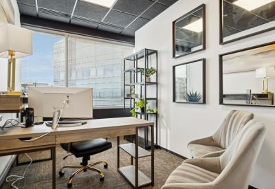 Private office suite with a wooden desk, plush gray chairs, and framed artwork.