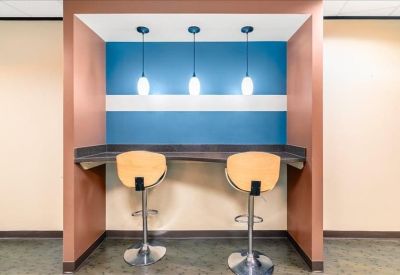 Breakout booth with a blue wall, pendant lighting, and two wooden bar stools.