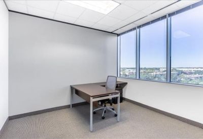 Bright private corner office with a dark wood desk and large windows overlooking the city.