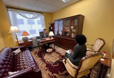 A traditional wood-paneled office suite with leather sofa, oriental rug, and built-in bookshelves.