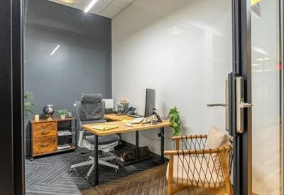 Private office with a wooden corner desk, ergonomic chair, and comfortable guest armchair.