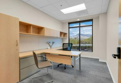 Private office suite with a wood-finish desk and large window.