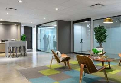 Modern lounge area with stylish wooden chairs, a colorful tiled rug, and glass-walled suites.