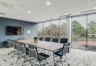 Professional conference room with a large table, black mesh chairs, and floor-to-ceiling windows.
