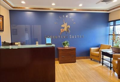 Branded reception area with a dark wood front desk, blue feature wall, and comfortable leather armchairs.