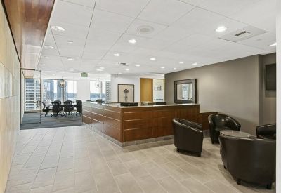Professional reception area with a wood-paneled desk and black leather lounge chairs.