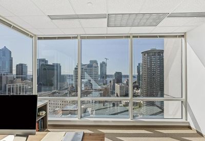 Private office workspace with a computer monitor and a wide window view of downtown skyscrapers.