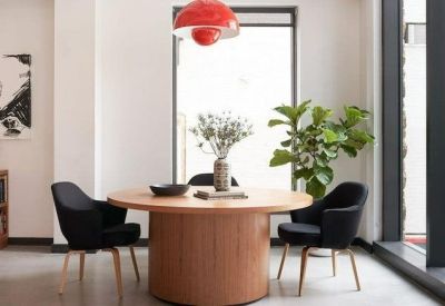 Sunlit meeting room featuring a round wooden table and modern black armchairs.