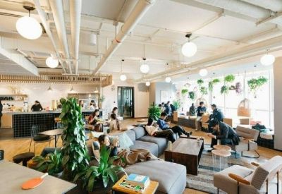 Bright coworking area with varied seating, many indoor plants, and large windows.
