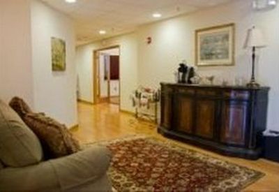 Waiting area with a patterned rug, comfortable seating, and a dark wood sideboard.