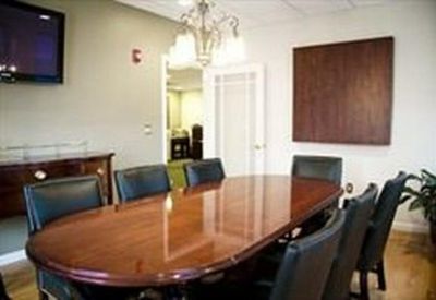 Professional boardroom featuring a polished wood table, leather chairs, and a chandelier.