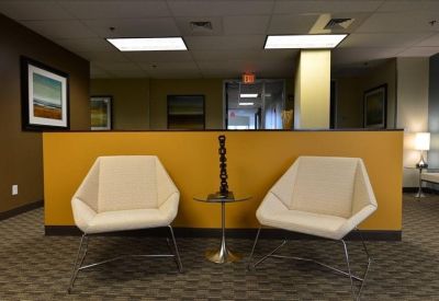 Reception waiting area featuring modern white geometric armchairs and a warm yellow wall.