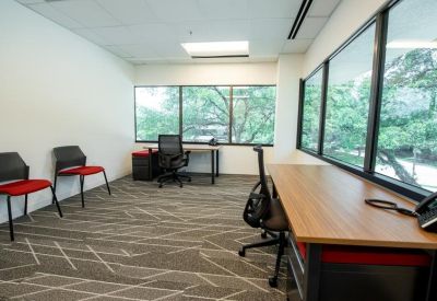 Private office suite with red-cushioned guest chairs and large windows.