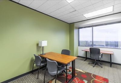 Private office featuring a green accent wall and dual workspaces with a window view.