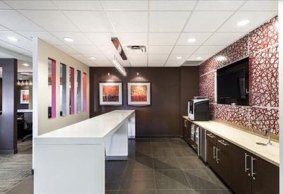 Modern breakroom with a long white breakfast bar, coffee machine, and patterned wallpaper.