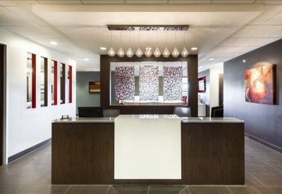 Professional reception desk with dark wood paneling, drop lighting, and abstract wall art.