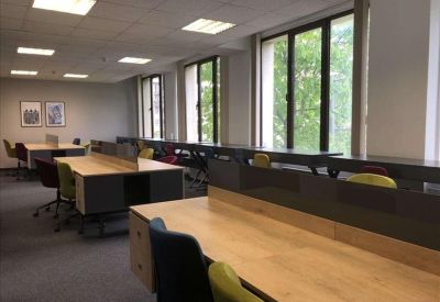 Private office with a wood desk, blue feature wall, and large window with city views.