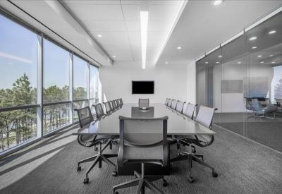 Spacious boardroom with a long glass table, grey chairs, and floor-to-ceiling windows.