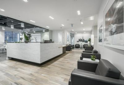 Modern reception area with a white stone desk and grey lounge seating.