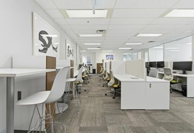 Bright open-plan office with white workstations and modern ergonomic chairs.