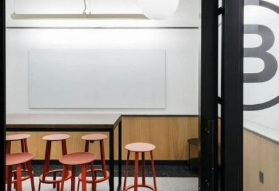 Small meeting room with a high table, red stools, and a large whiteboard.