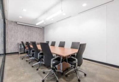 Professional meeting room with a long wooden table and ergonomic black chairs.