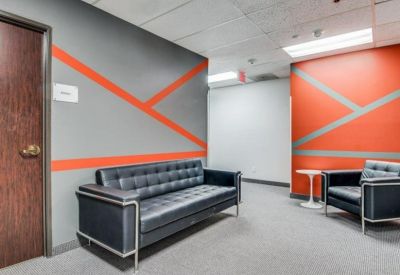 Casual waiting area with black leather seating and orange geometric wall graphics.