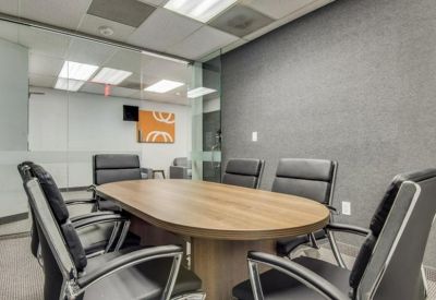 Professional meeting room with a wooden table, black leather chairs, and a grey feature wall.