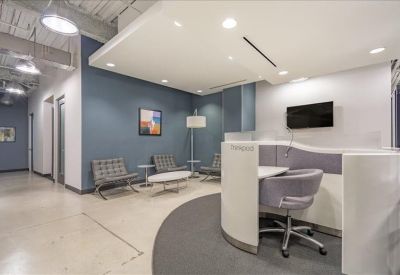 Contemporary breakout area with a curved white desk and lounge seating.