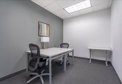 Private two-person office suite with grey feature wall and mesh chairs.